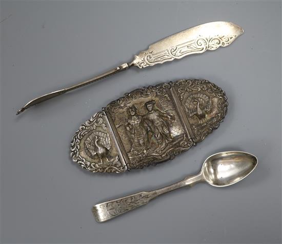 An Indian white metal belt buckle, a 19th century Russian silver teaspoon and a continental butter knife.